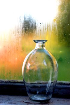 Antique glassy bottle on the windowsill of porch.