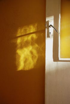 White door and the sun's reflection on a yellow wall