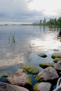 Lake shore before the storm with stones on the coast