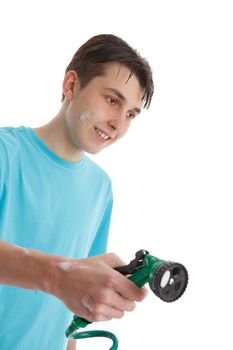A teenage boy using a garden hose and trigger nozzle spray attachment.