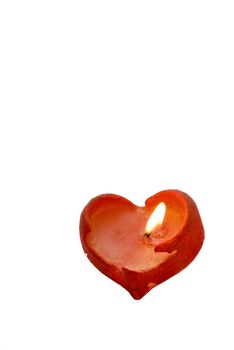 Red heart-shaped candle burning on a white background