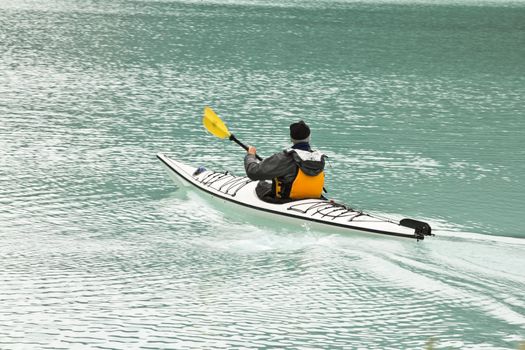 Paddling in a canoe on the beautiful turquoise colored Lake Louis against the backdrop of the majestic mountains of the Canadian Rockies partially covered with fog