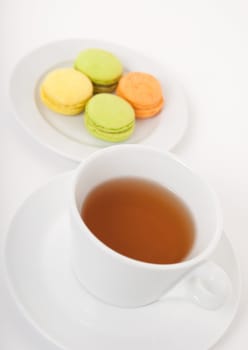 White cup of tea and colorful macarons for dessert.