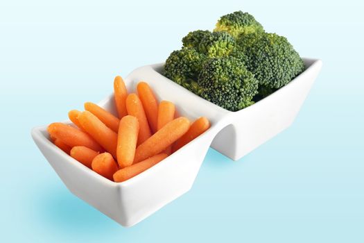 Healthy food choice from the vegetable garden: carrot and broccoli in cute white serving plate.