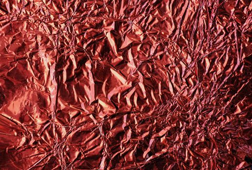 Great metallic background with many details: macro of crinkled red aluminum foil wrapping paper.
