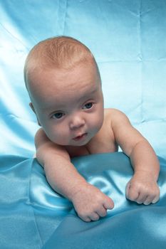 three month old baby laying on a blue satin sheet