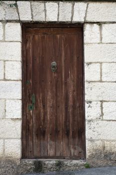 Old weathered wooden door in stone building.