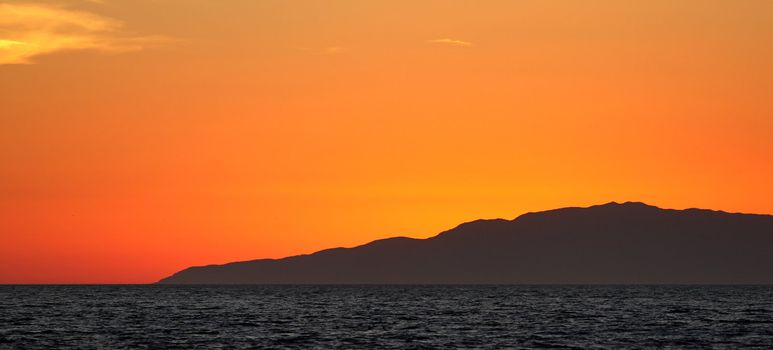 Sunset over the ocean with an island in the background