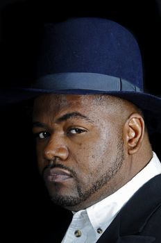 young bearded African American man in a fedora isolated on a black background