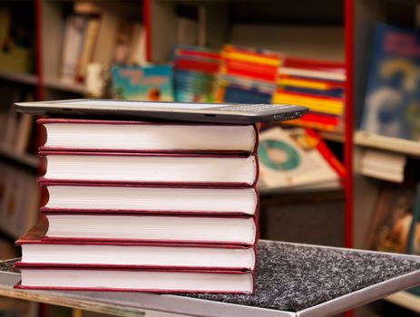 Stack of colorful books with electronic book reader