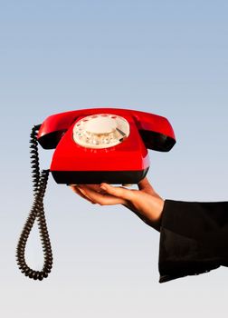 Hand holding an old fashioned red phone