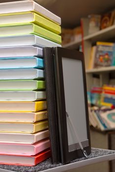 Stack of colorful books with electronic book reader