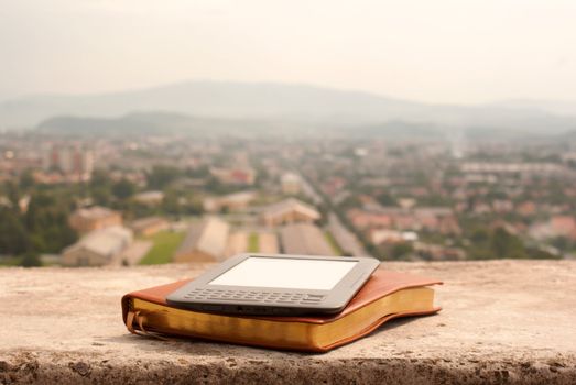 Electronic book reader laying on the book outdoors