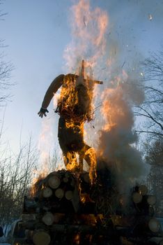 Mardi gras winter jackstraw effigy in spring fire