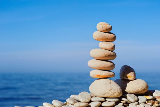 Balancing white pebbles each other on the seashore