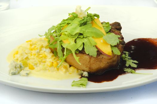 Meat dressed with greens, peach and a cherry sauce creamed corn and blue cheese