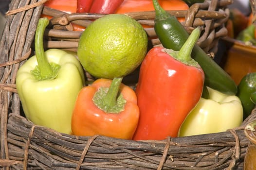 Basket of a variety multicolored types of peppers and a lime