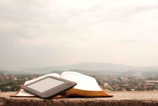 Electronic book reader laying on the book outdoors