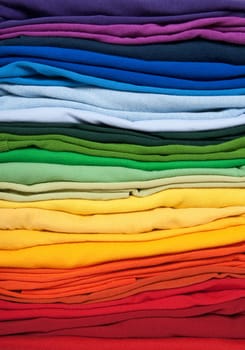 Rainbow clothes background. Pile of bright folded clothes.