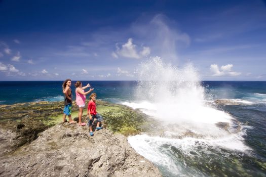 Three people observing the blowholes putting on a specatacular display at Houma on the western side of Tongatapu Island in the Pacific.