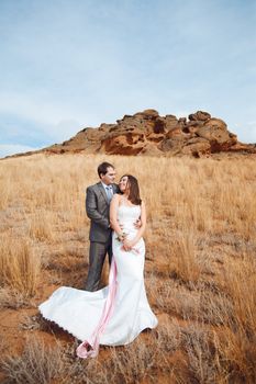 bride and groom in the field with mountain