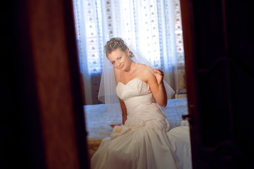 bride waiting for a groom under the veil - look through the doors