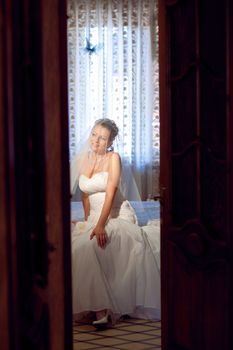 bride waiting for a groom under the veil - look through the doors