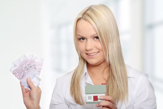 Beautiful young woman holding euros bills and house model over white