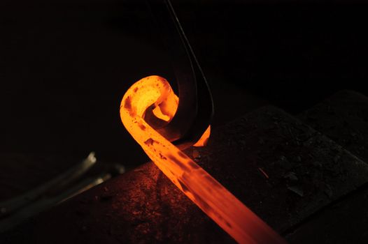 Blacksmith working on decorative handrail bending the heated metal