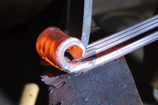 Blacksmith working on decorative handrail bending the heated metal