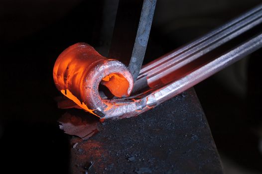 Blacksmith working on decorative handrail bending the heated metal