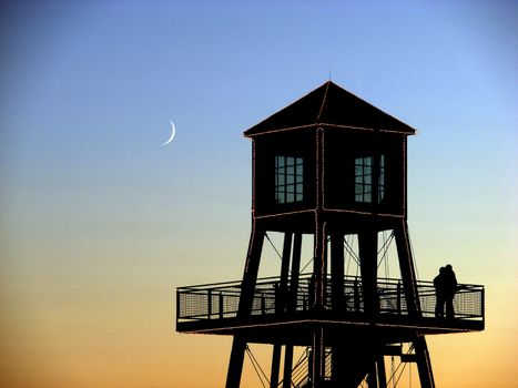 Moon over couple in observation tower on Memphremagog Lake in Magog, Province of Quebec, Canada