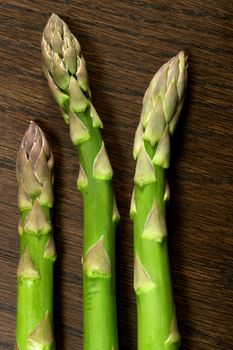 Three asparagus tips on a wooden table.
