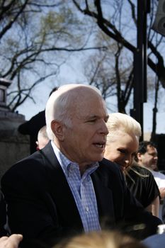 John McCain after a speech, gives handshakes to people, with Cindy McCain behind him.