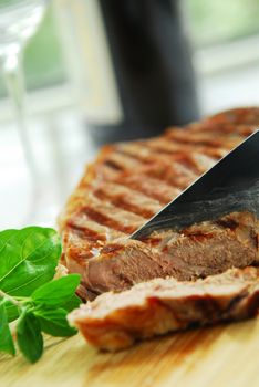 Grilled New York steak being cut on a cutting board