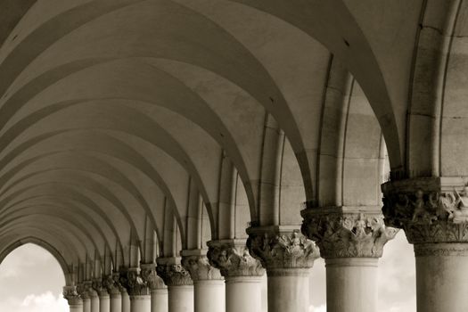 Sepia-toned row of arches and columns in Venice Italy.
