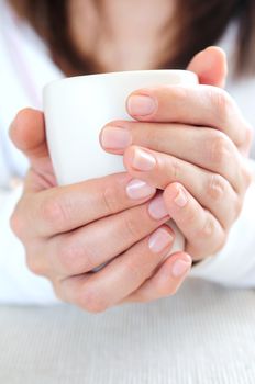 Hands of a mature woman holding a cup 