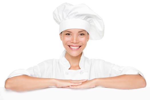 Chef or baker woman showing blank empty billboard sign. Beautiful smiling happy chef leaning on placard banner with copy space for menu or other text.