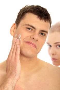 Happy man after shaving applying moisturizing cream upon his face