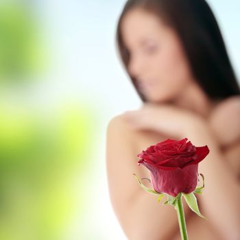 Beautiful red rose against young nude caucasian woman in background