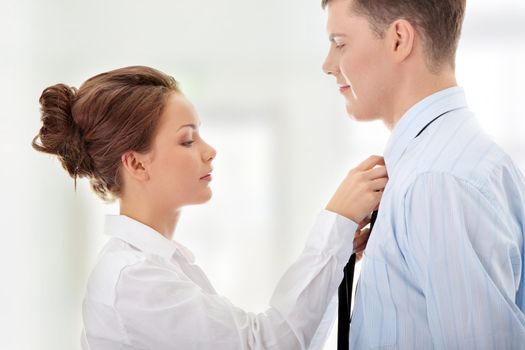 Businesswoman knotting the necktie of the businessman, helping and assisting him getting dressed.