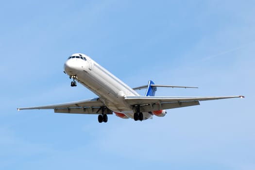 Plane is going to land in an airport. Blue sky.