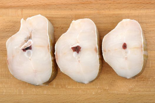 steaks of cod on a wooden cutting board