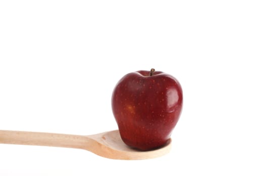 Apple on a wooden spoon isolated against a white background