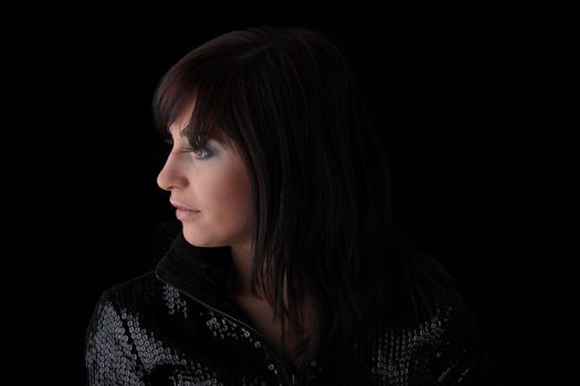 Beautiful young woman with long healthy dark hair on dark black background.