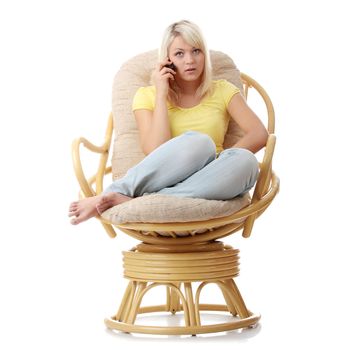 Young blond woman sitting on armchair with cell phone isolated