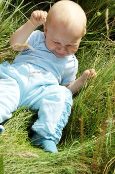 Crying baby boy outdoors at sunny summer day