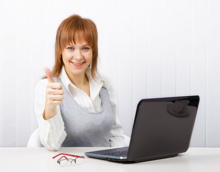 Positive smiling businesswoman with a laptop with a thumb up
