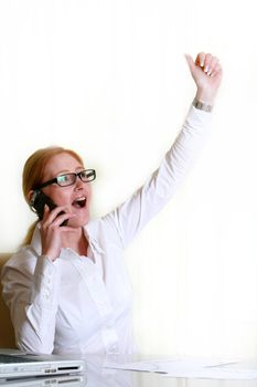 Young business woman at desk cheering and happy
