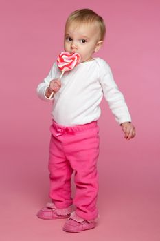 Toddler girl eating lolipop candy